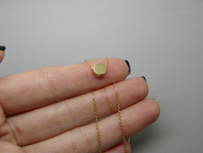 May include: A gold chain necklace with a small, round pendant.