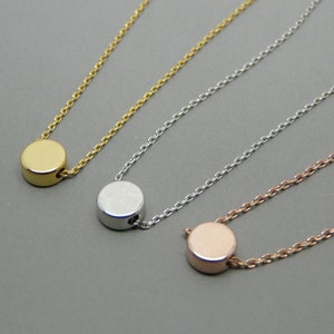 May include: Three delicate necklaces with a simple circle pendant. The necklaces are gold, silver, and rose gold.