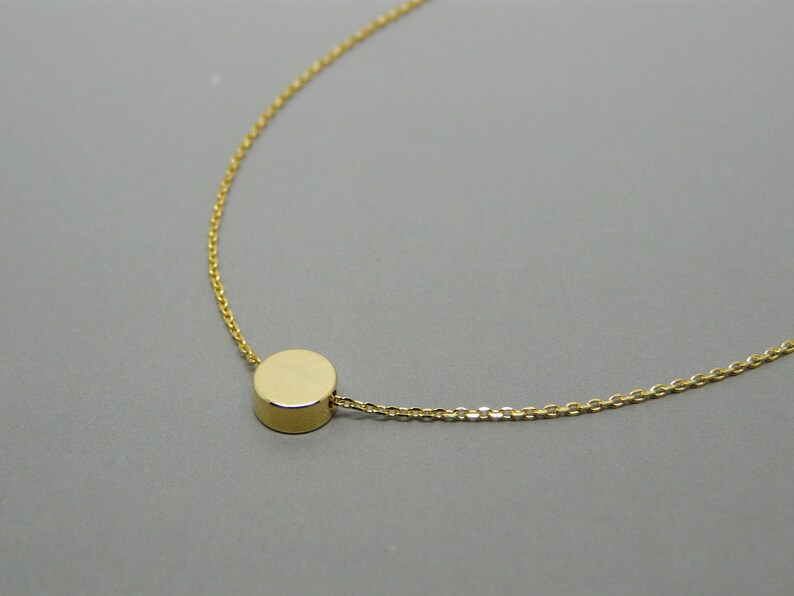 May include: A gold chain necklace with a small, round pendant.