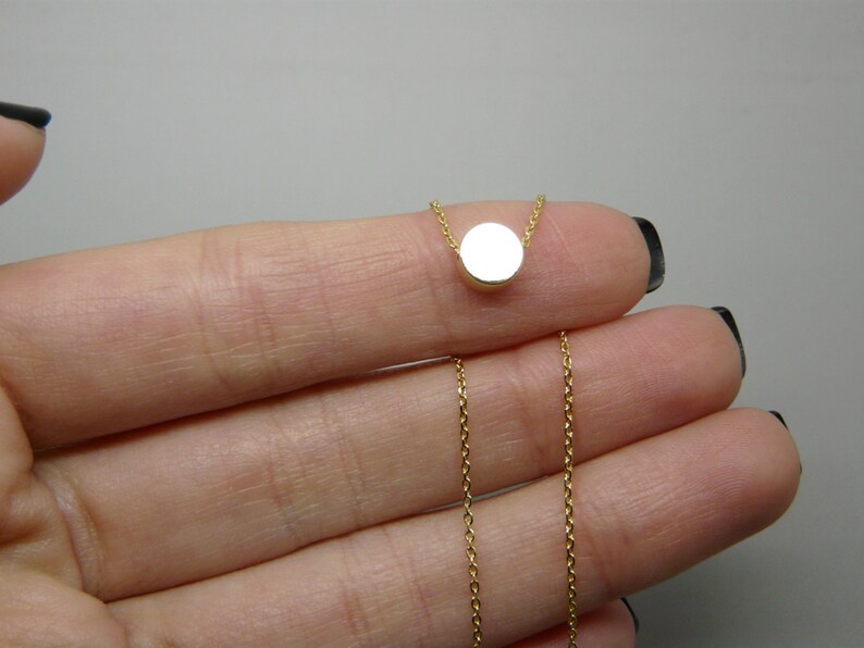 May include: A gold chain necklace with a small, round pendant.