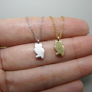 May include: Two owl pendant necklaces. One is silver-colored, the other is gold-colored. Each owl pendant is a silhouette design, hanging from a delicate chain. The necklaces are displayed against a neutral background.
