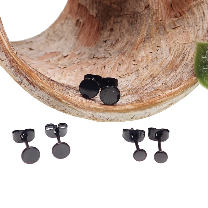 May include: Three pairs of black stud earrings. The earrings are small and round, with a smooth, polished finish.