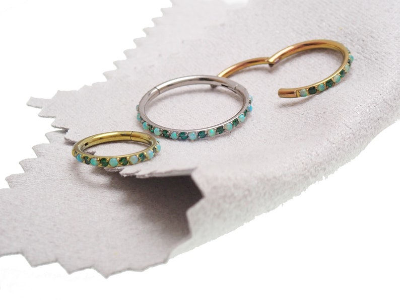 Puede incluir: Tres aros de aro sin costuras de oro, plata y oro rosa con una fila de piedras turquesa y verdes.