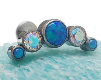 May include: A silver body jewellery piece with five blue and iridescent gemstones. The gemstones are arranged in a curved line.