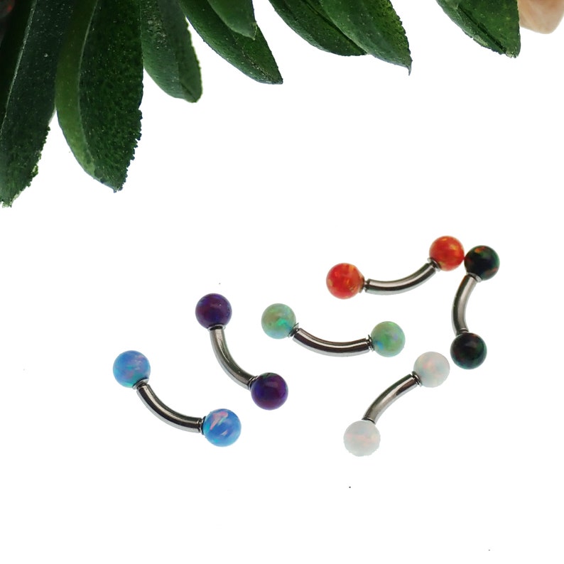 May include: A collection of four curved barbell body jewelry pieces featuring metallic silver-toned shafts and spherical ends. Each end is adorned with a smooth, colorful opal-like stone in shades of blue, purple, light green, orange, and white.