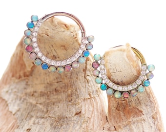 May include: Two silver hoop earrings with a row of iridescent opal gemstones and a row of clear cubic zirconia gemstones.