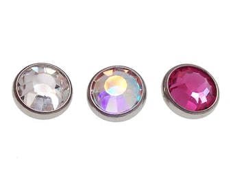 May include: Three round, faceted gemstones in a row. One is clear, one has an iridescent sheen, and the third is a deep pink. Each gem is set in a silver-colored bezel.