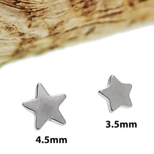 May include: Two silver-toned star-shaped studs. One star measures 4.5mm and the other star measures 3.5mm. The studs have a smooth, metallic finish and are presented against a plain white background with a textured brown element at the top.