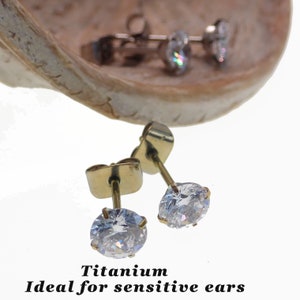 May include: A pair of gold titanium earrings with clear round cubic zirconia stones.  Titanium is ideal for sensitive ears.