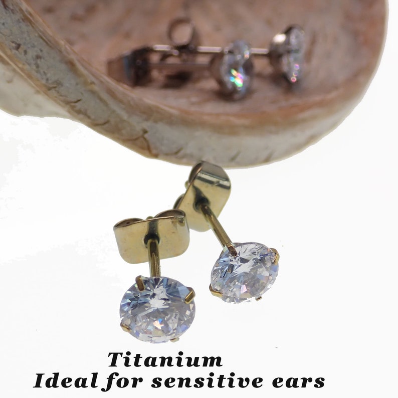 May include: A pair of gold titanium earrings with clear round cubic zirconia stones.  Titanium is ideal for sensitive ears.