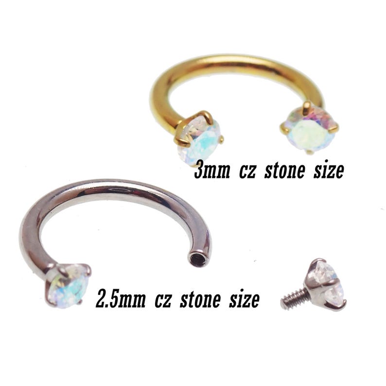 May include: A selection of body jewellery, including a gold-coloured horseshoe ring with 3mm CZ stones, a silver horseshoe ring with 2.5mm CZ stones, and a screw-on stud. Text reads "3mm cz stone size" and "2.5mm cz stone size".