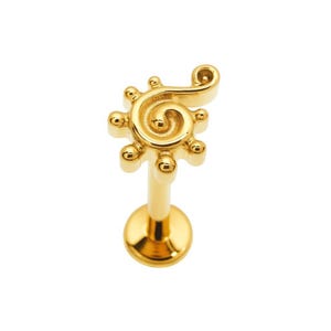 May include: A gold-coloured lip piercing stud with a distinctive design. The stud has a spiral shape with small, round accents and a post for insertion. The jewellery is designed to be worn on the lip.