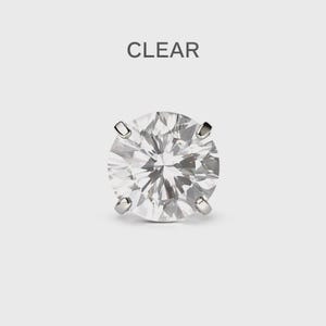 May include: A clear, round-cut diamond stud earring with four prongs. The word "CLEAR" is printed above the earring. The earring is set against a light grey background.