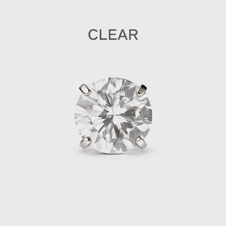 May include: A clear, round-cut diamond stud earring with four prongs. The word "CLEAR" is printed above the earring. The earring is set against a light grey background.