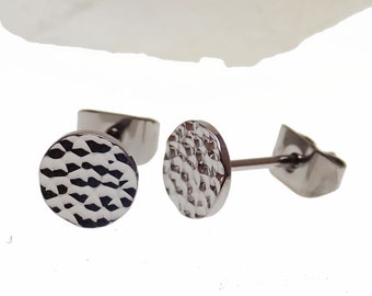 Könnte beinhalten: Ein Paar silberfarbene Ohrstecker mit gehammerter Textur. Die Ohrringe sind rund und haben einen Stecker und einen Verschluss. Die Ohrringe werden auf weißem Hintergrund präsentiert.