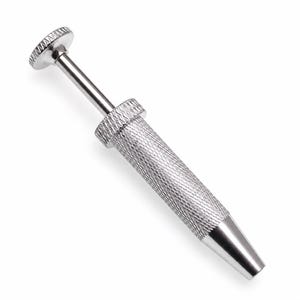 Op de afbeelding: Een zilverkleurig metalen grijptool met een cilindrische handgreep voorzien van een kruislings gekartelde textuur voor grip, een gladde taps toelopende punt en een veerbelast plunjermechanisme aan de bovenzijde met een ronde, textuurrijke drukknop.