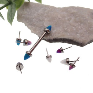 May include: A set of six surgical steel body jewelry pieces with opal stone accents. The pieces include a barbell with two blue and purple opal stones, and five individual studs with opal stones in blue, purple, and white.