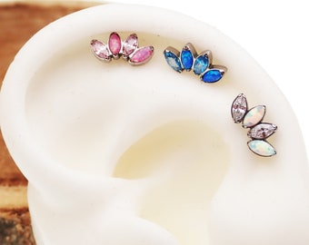 May include: Three ear piercings with gemstone clusters. One features pink and rose-coloured stones, another has blue stones, and the third has white and opal-coloured stones. The jewellery is displayed on a white ear model, showcasing the designs.