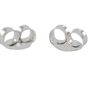 May include: Two silver-colored metal earring backs, each featuring a flat circular base and two curved loops designed to grip an earring post securely. These components are metallic, shiny, and have a smooth, polished finish throughout.