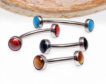 Può includere: Quattro gioielli per il corpo a barra curva con aste in argento metallizzato. Ogni estremità presenta una pietra cabochon rotonda e liscia in diversi colori: blu brillante, rosso intenso, nero solido e un motivo occhio di tigre marrone.