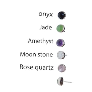 May include: Stud earrings with various gemstones, including onyx, jade, amethyst, moonstone, and rose quartz. Each earring features a round gemstone set in a silver-colored bezel. The names of the gemstones are listed next to each earring.