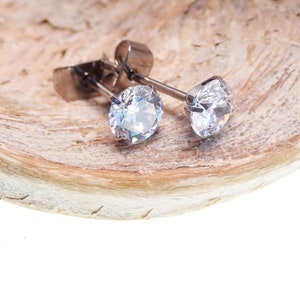May include: A pair of silver stud earrings with clear round cubic zirconia stones.