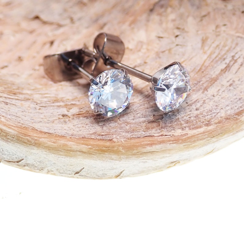 May include: A pair of silver stud earrings with clear round cubic zirconia stones.