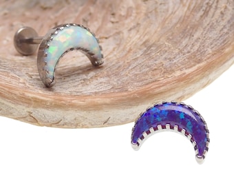 May include: Two crescent moon shaped opal earrings with a silver setting. The opal on the left is white and the opal on the right is purple.