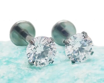 May include: A pair of silver stud earrings with clear round cubic zirconia stones.