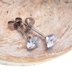 May include: A pair of silver stud earrings with clear round cubic zirconia stones.