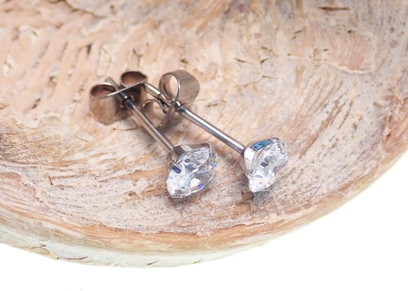 May include: A pair of silver stud earrings with clear round cubic zirconia stones.