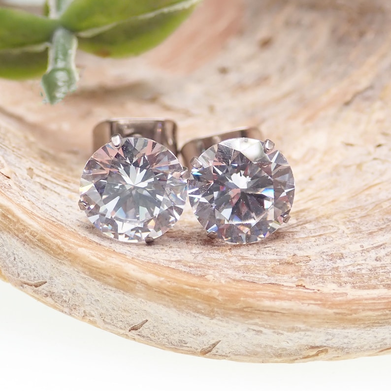 May include: A pair of silver stud earrings with large, clear, round cubic zirconia stones.