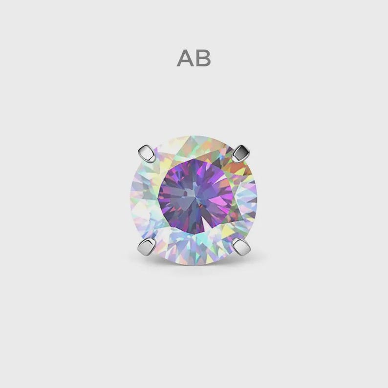 May include: A single, round, iridescent gemstone with a silver setting. The gem displays a spectrum of colours, including purple, blue, and yellow, and is set against a light grey background. The letters "AB" are above the gem.