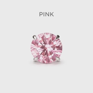May include: A single pink gemstone earring with a round cut, held by four silver prongs. The word "PINK" is displayed above the earring against a white background. The gemstone has a faceted surface.