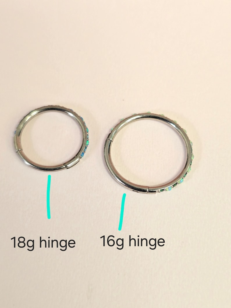 Puede incluir: Dos pendientes de aro con bisagra de plata con detalles de &oacute;palo. El pendiente de la izquierda est&aacute; etiquetado como "18g hinge" y el pendiente de la derecha est&aacute; etiquetado como "16g hinge".
