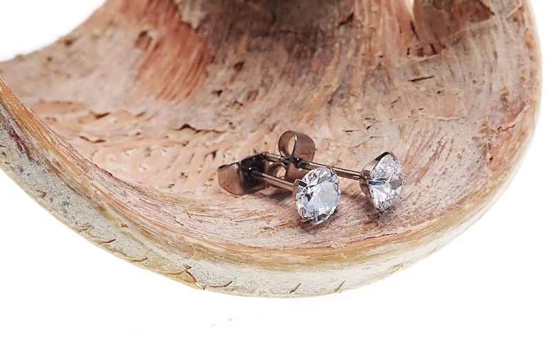 May include: A pair of silver stud earrings with clear round cubic zirconia stones.