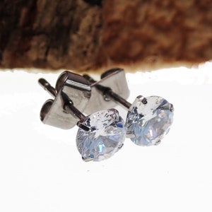 May include: A pair of silver stud earrings with clear round cubic zirconia stones.