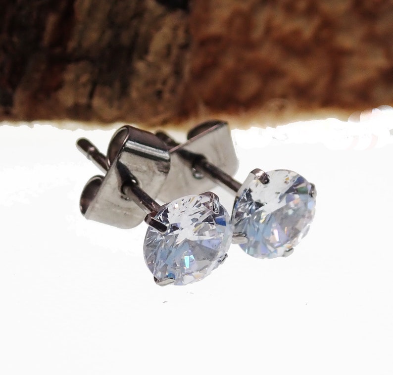May include: A pair of silver stud earrings with clear round cubic zirconia stones.