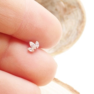 May include: A small, delicate, gold earring with three marquise-shaped clear stones.