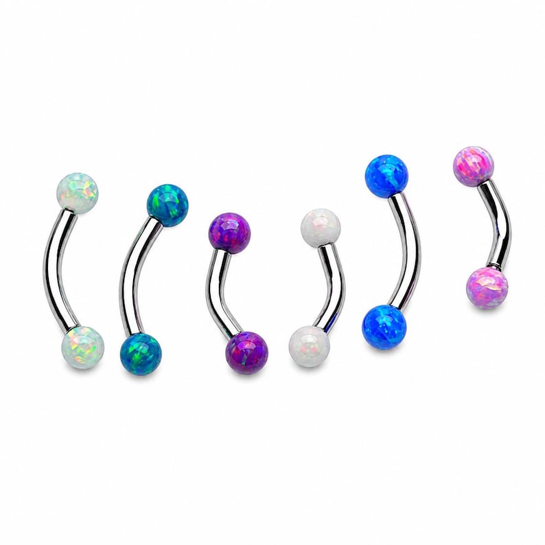 May include: A collection of six curved barbell body jewelry pieces, each featuring two spherical ends with iridescent opal-like finishes in white, blue, and purple hues, set on polished silver-toned metal curved bars for various piercings.