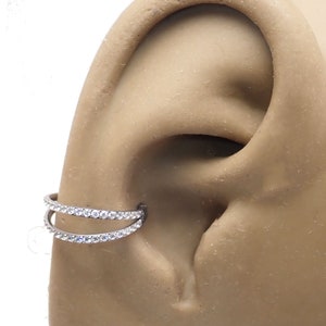 May include: A silver double row ear cuff with clear cubic zirconia stones.