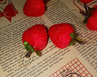 May include: A close-up of a craft project for making a reindeer ornament. The image shows red felt shapes, pipe cleaners, and a gridded pattern for cutting out the reindeer's head. The text "Insert Ear Here" is visible on the gridded pattern.