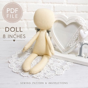 May include: A beige fabric doll measuring 8 inches in height, accompanied by a white heart-shaped frame with lace trim. The image includes text stating PDF FILE, DOLL 8 INCHES, and SEWING PATTERN & INSTRUCTIONS, presented on a white lace doily.