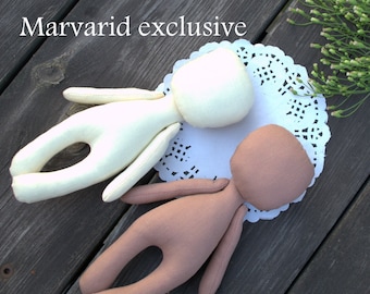 Op de afbeelding: Twee ongevulde stoffen poppen, een witte en een bruine, liggend op een witte doily. De poppen missen gezichten en hebben lange ledematen. De tekst "Marvarid exclusive" is zichtbaar in de linkerbovenhoek van de afbeelding.