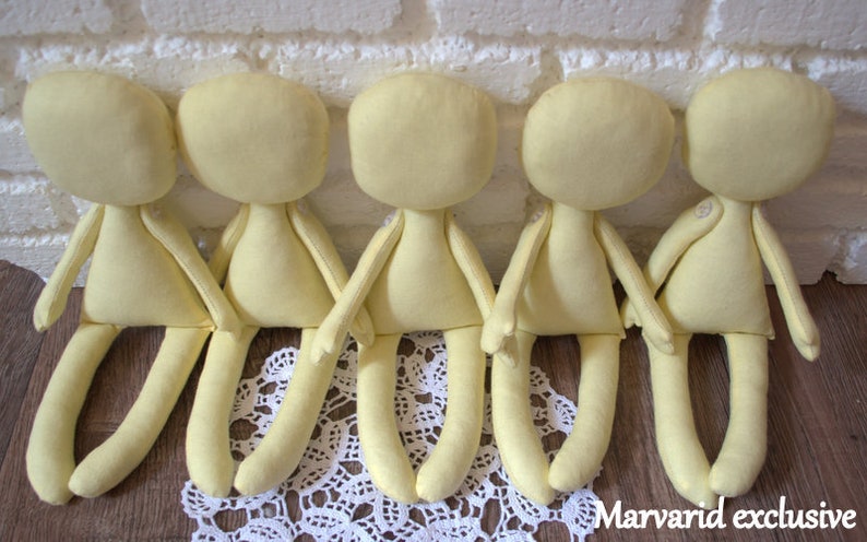 May include: Five unpainted yellow fabric doll bodies with limbs, sitting on a white lace doily.  The dolls are ready for customizing.