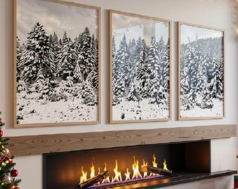 May include: A living room interior featuring three framed black and white prints of a snowy pine forest hanging above a long, linear fireplace with glowing flames. A decorated Christmas tree stands to the left, and a large window reveals a snowy landscape.
