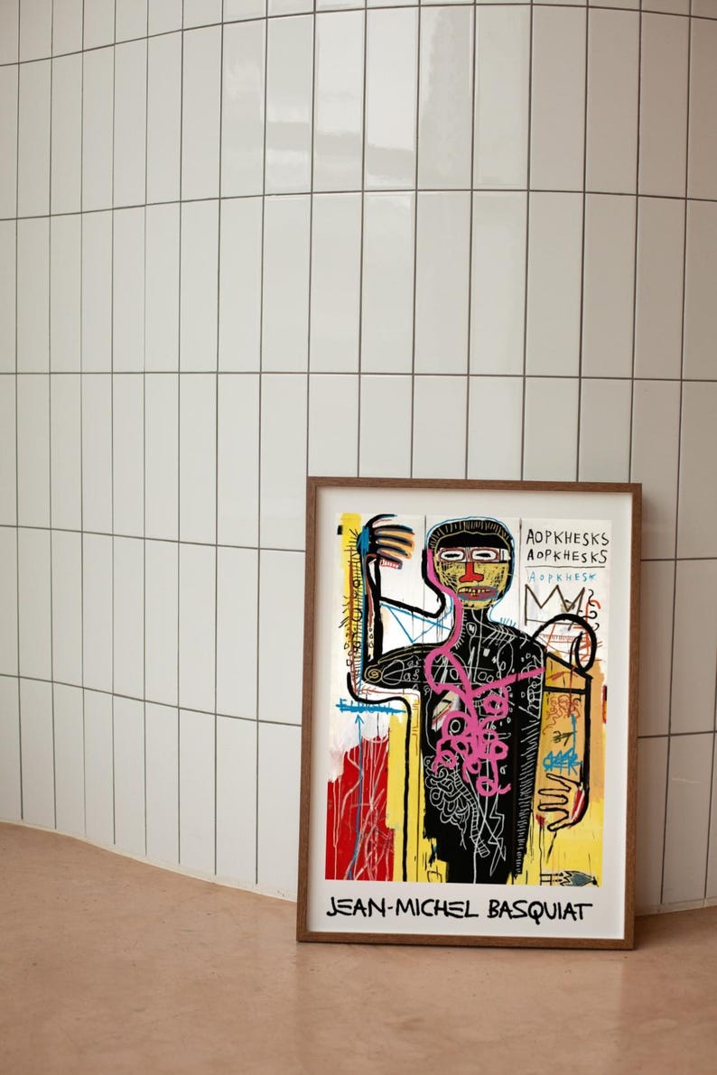 Puede incluir: Una impresi&oacute;n art&iacute;stica enmarcada con una obra de arte de Jean-Michel Basquiat. La impresi&oacute;n muestra una figura con un contorno negro, un torso rosa y un fondo amarillo y rojo. El nombre del artista est&aacute; impreso en la parte inferior.
