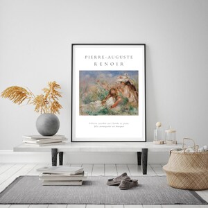 Puede incluir: Una impresi&oacute;n art&iacute;stica enmarcada que presenta una pintura de Pierre-Auguste Renoir. La obra de arte representa a dos figuras en un campo de flores. La impresi&oacute;n est&aacute; en un marco negro e incluye el nombre del artista y el t&iacute;tulo de la pintura.
