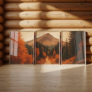 Peut inclure: Un triptyque composé de trois cadres muraux présentant un paysage continu. L'œuvre illustre un sommet de montagne, un chemin de terre sinueux et des forêts denses aux feuillages orange vif et vert foncé sous une lumière douce.