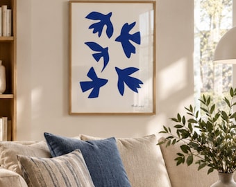 May include: A framed wall art print featuring five abstract blue bird silhouettes arranged on a cream-colored background. The artwork is enclosed in a light-toned wooden frame and displays a small signature in the bottom right corner.